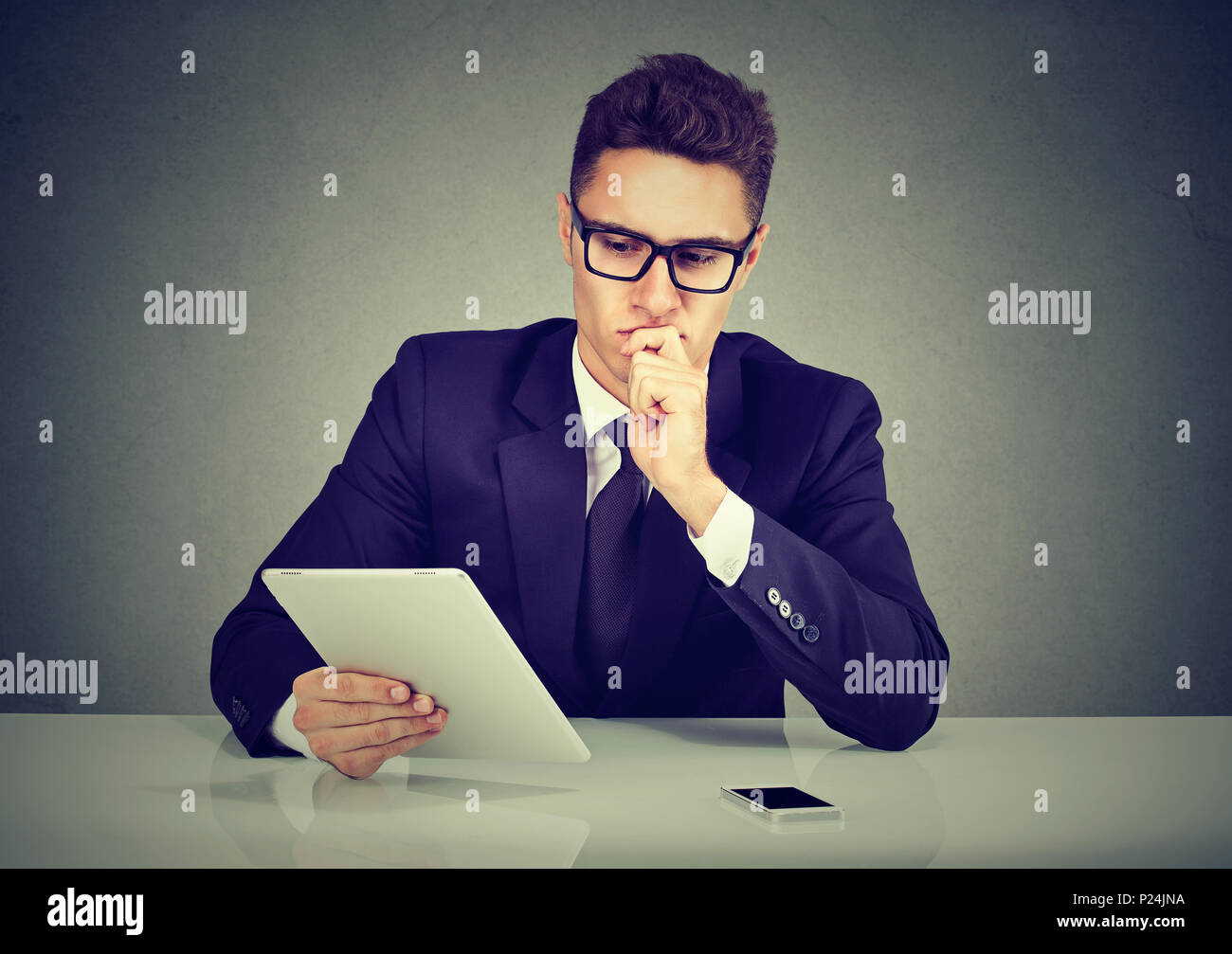 Ernsthafte hübscher junger Geschäftsmann auf Tablet-PC eine Auswahl suchen Stockfoto