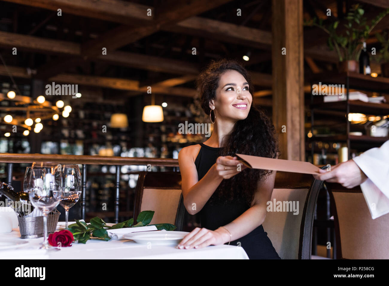 Junge schöne Frau unter Menü von Kellner im Restaurant Stockfoto