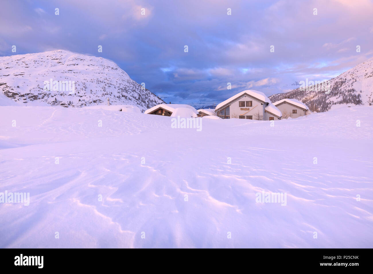 Schnee durch den Wind bei einigen traditionellen Hütten am Simplonpass geformte während des Sonnenuntergangs. Simplon, Kanton Wallis/Wallis, Schweiz. Stockfoto