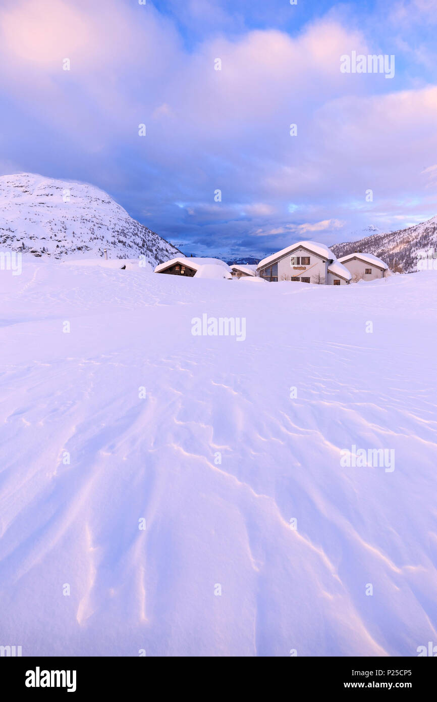 Schnee durch den Wind bei einigen traditionellen Hütten am Simplonpass geformte während des Sonnenuntergangs. Simplon, Kanton Wallis/Wallis, Schweiz. Stockfoto