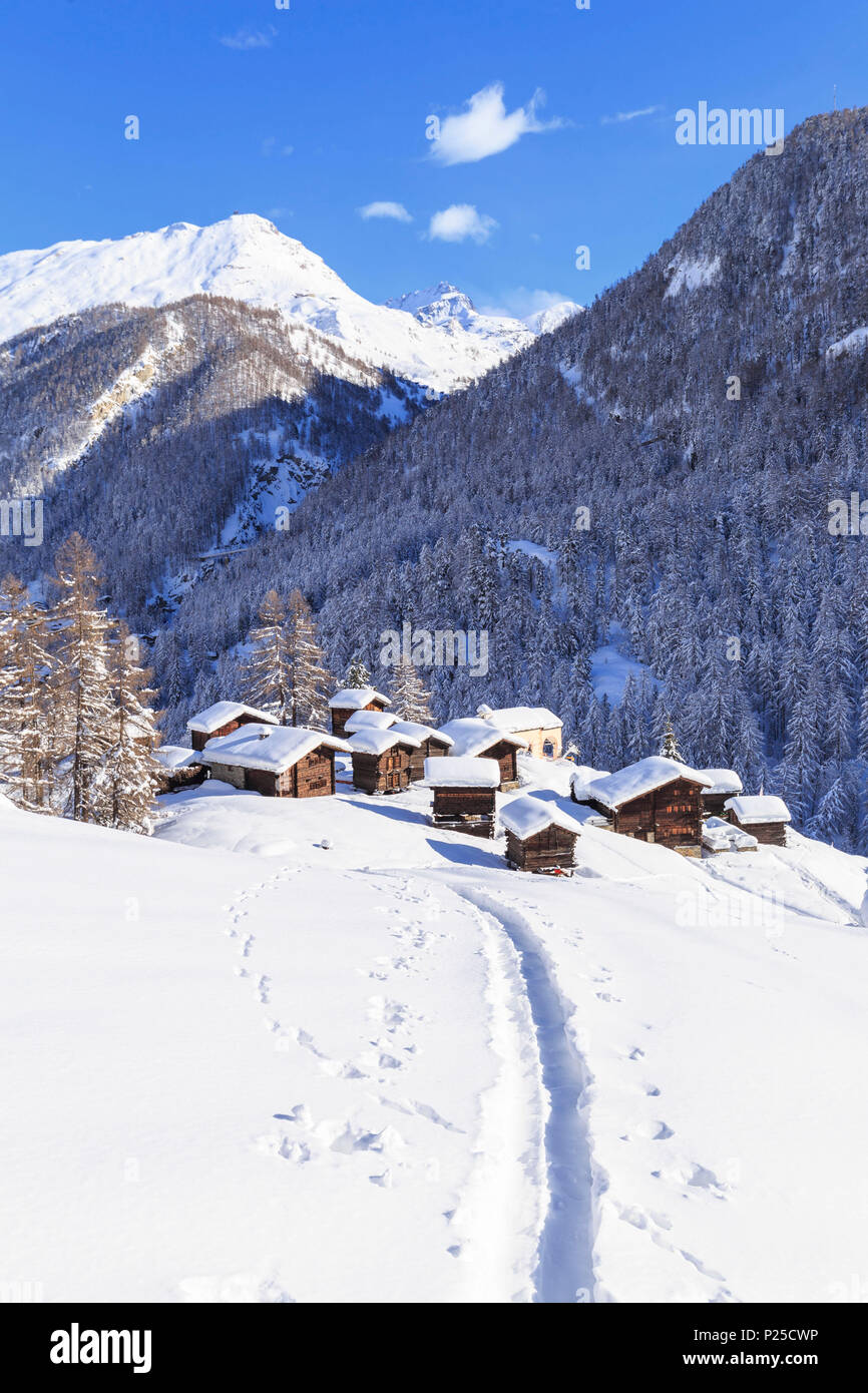 Eine Spur im Schnee führt zu den traditionellen Hütten in Blatten. Zermatt, Wallis/Wallis, Schweiz. Stockfoto