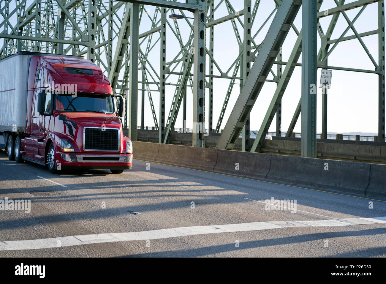 Red Big Rig leistungsstarke Long Haul Semi Truck mit trockenen van Auflieger gehen auf die Interstate zeichnen Brücke über den Columbia River für die Lieferung von commerci Stockfoto