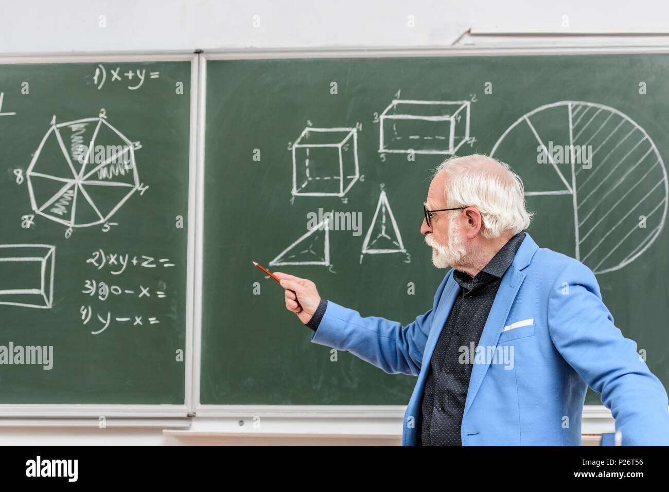 Graue Haare Professor auf etwas mit Bleistift auf Tafel zeigend Stockfoto