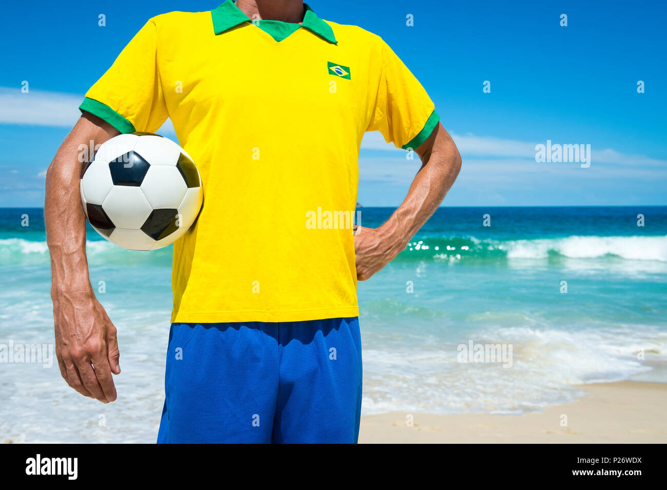 Fußball-Spieler in Brasilien Flagge shirt Holding Fußball am Strand von Ipanema in Rio de Janeiro Stockfoto