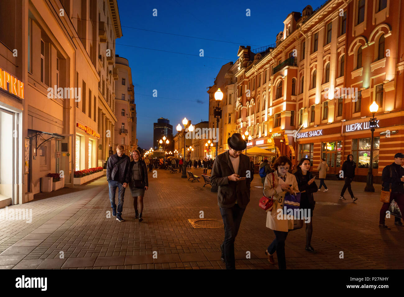 Moskau, Russland - 21. September 2017: Volk und historischen Gebäude, das von warmen Licht Arbat dekoriert Straße zu Fuß in der Dämmerung mit blauem Himmel. Stockfoto