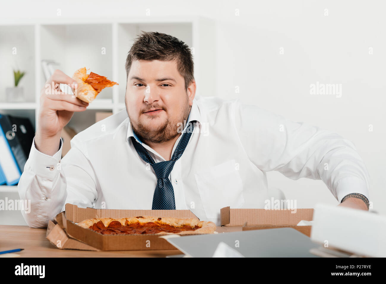 Übergewicht Geschäftsmann essen Pizza am Arbeitsplatz Stockfoto