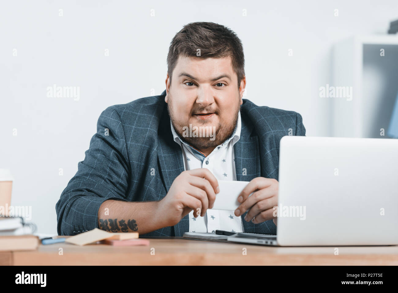 Fat Geschäftsmann im Anzug arbeiten mit Smartphone und Laptop am Arbeitsplatz Stockfoto