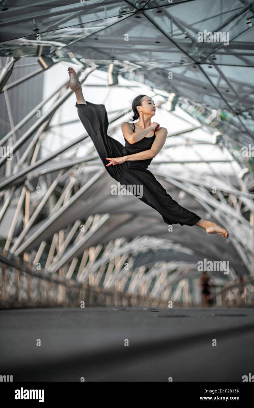 Schöne junge Mädchen tanzen auf einer Brücke, mit schwarzen Stockfoto