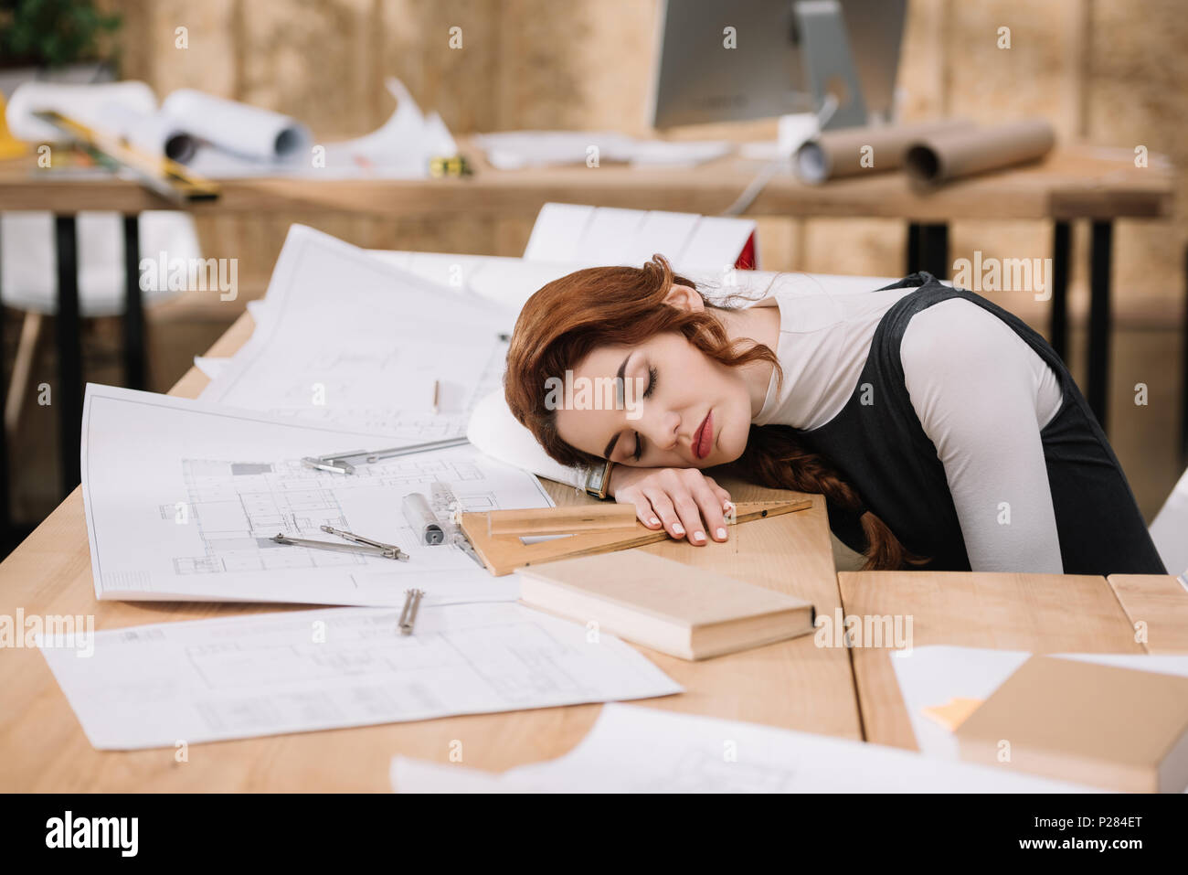 Überarbeitet weiblichen Architekten schlafen auf Baupläne am Arbeitsplatz Stockfoto