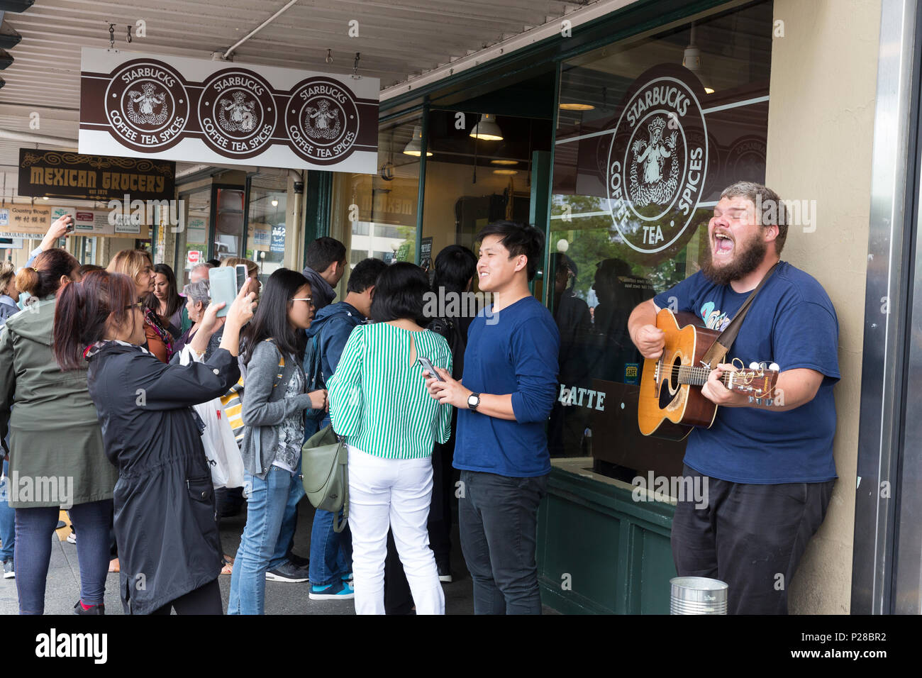 Seattle, Washington: Eine Masse von Touristen Cue am Pike Place Starbucks Store als Gaukler in der Nähe singt. Allgemein als das Original Starbucks bekannt, Stockfoto