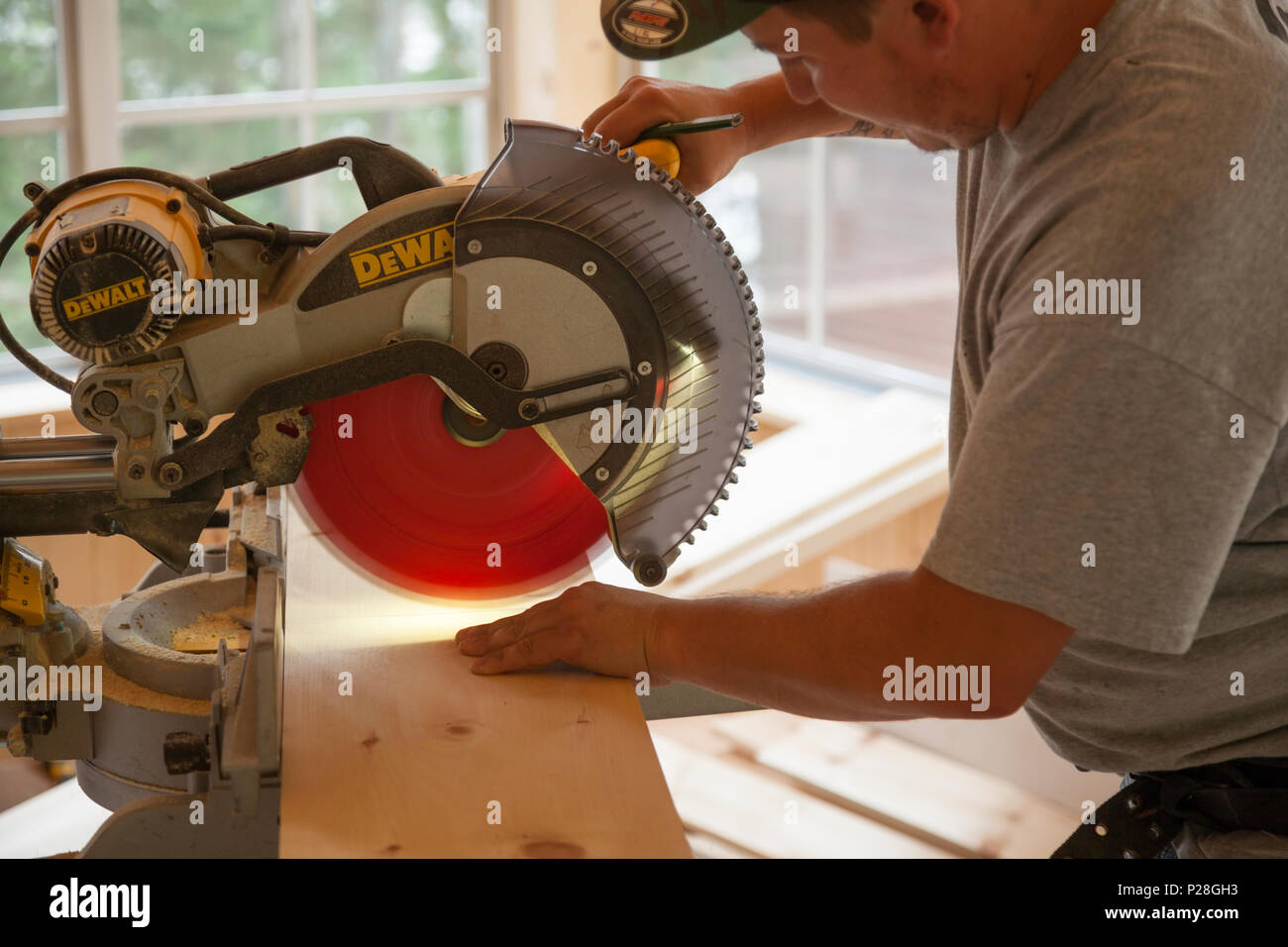 Ein Bauarbeiter mit einer Kreissäge ein Holzbrett zu schneiden. Stockfoto