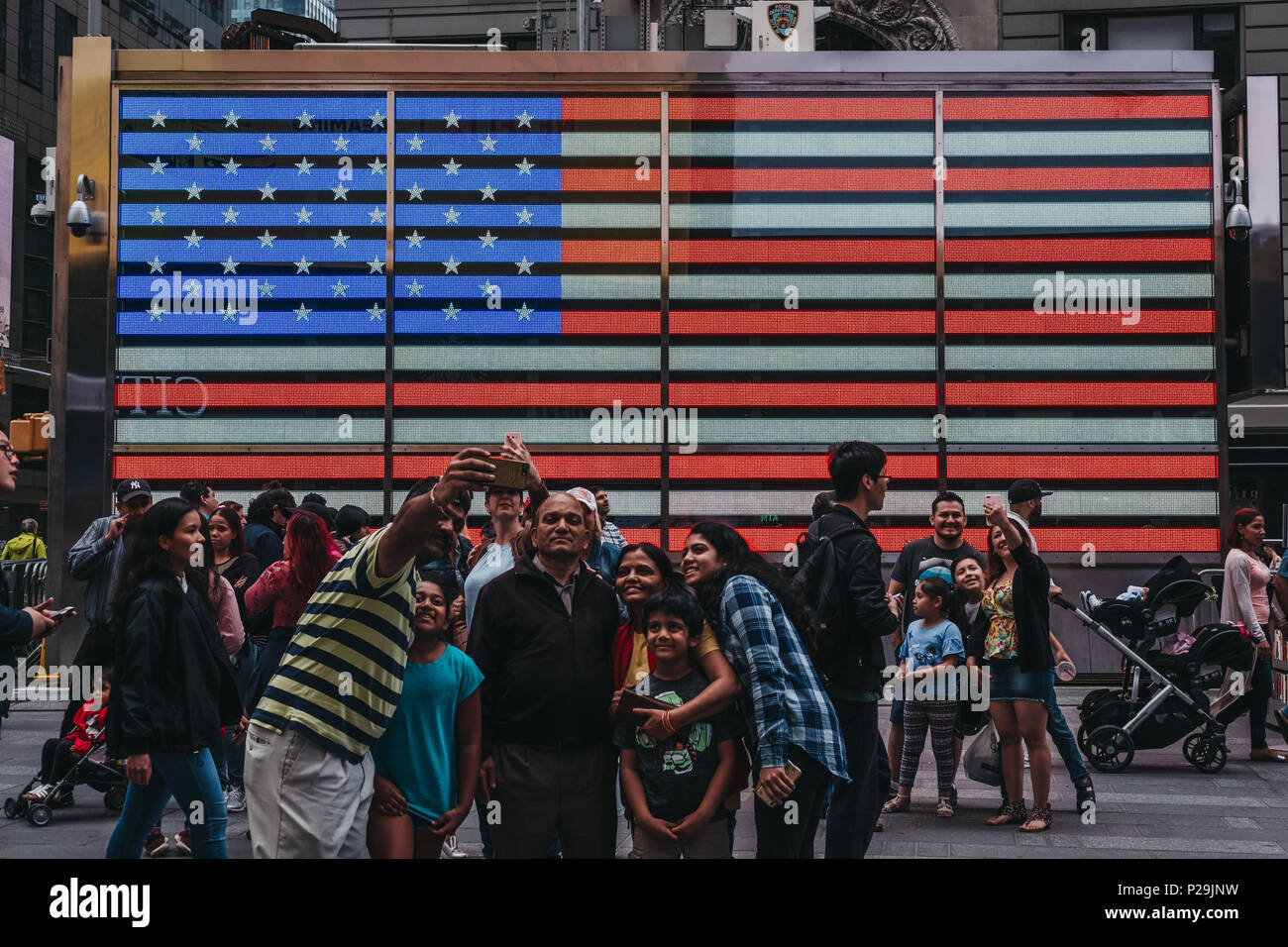 Touristen, die in selfies aus auf einem grossen LED-amerikanische Flagge in Times Square, New, USA. New York ist eine der meist besuchten Städte in der Welt. Stockfoto