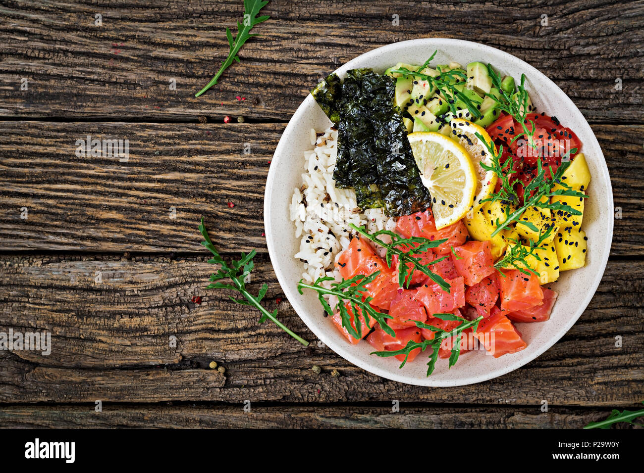 Hawaiian Lachs Fisch poke Schüssel mit Reis, Mango, Avocado, Tomate, Sesamsamen und Algen. Buddha Schüssel. Diät essen. Ansicht von oben. Flach Stockfoto