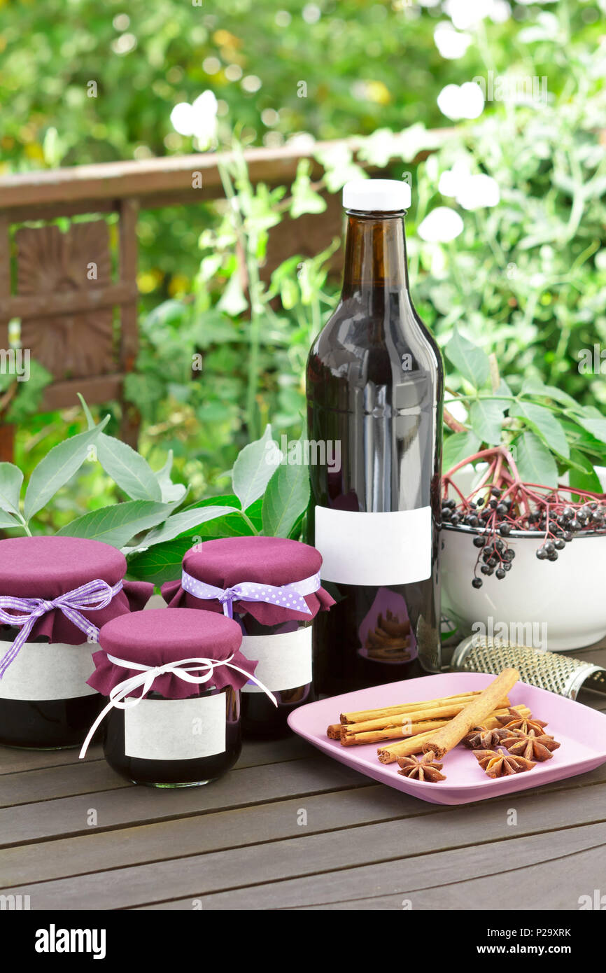 Hausgemachte Holunder Gelee und Saft in Flaschen und Gläsern mit holunderbeeren auf einem hölzernen Tisch im Freien vor der grüne Blätter, kopieren. Stockfoto