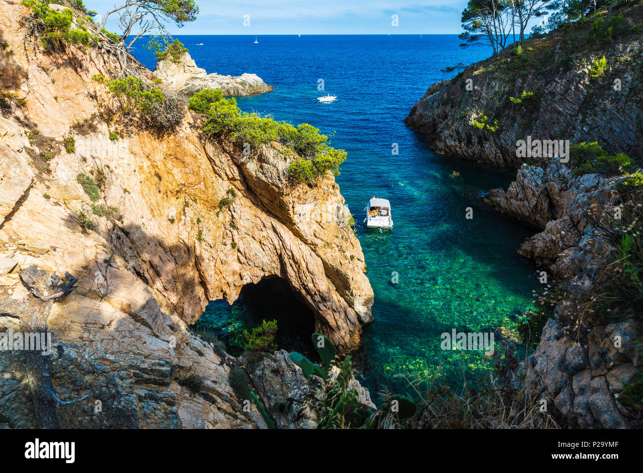 Yacht Neben einer Klippe mit einer Höhle im kristallklaren Wasser des Mittelmeers in Palamós, Costa Brava, Girona, Katalonien, Spanien Stockfoto