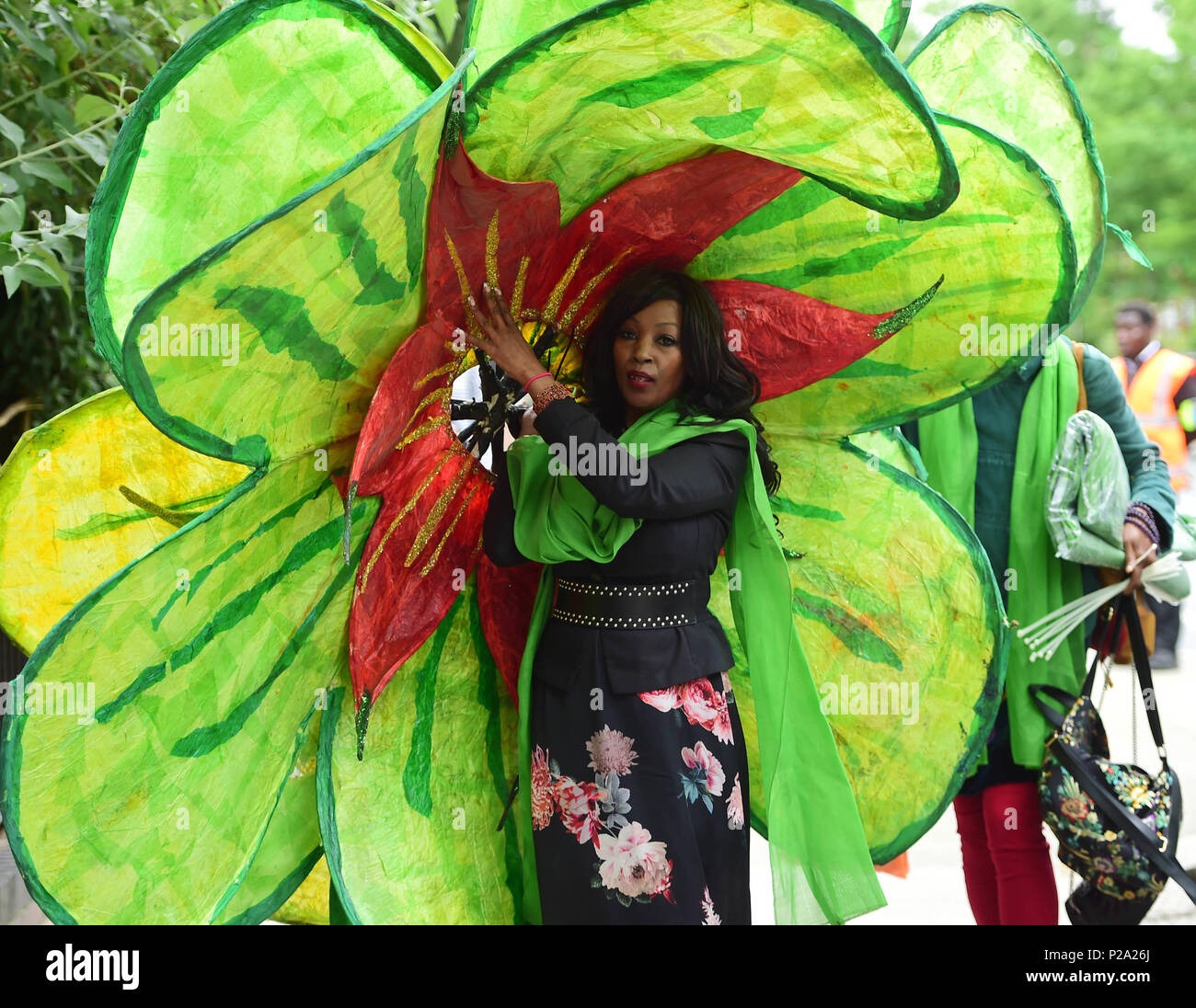 Eine Frau kommt in der St. Helen's Church, South Kensington, mit einem großen Blume Tribut, vor einer Grenfell Turm brand Gedenkgottesdienst fuer ein Jahr seit der Flamme, die 72 Menschenleben gefordert. Stockfoto