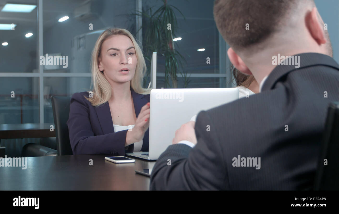 Blonde junge Geschäftsfrau, die die Arbeit mit Kollegen an der Konferenz im Büro kommunizieren. Stockfoto