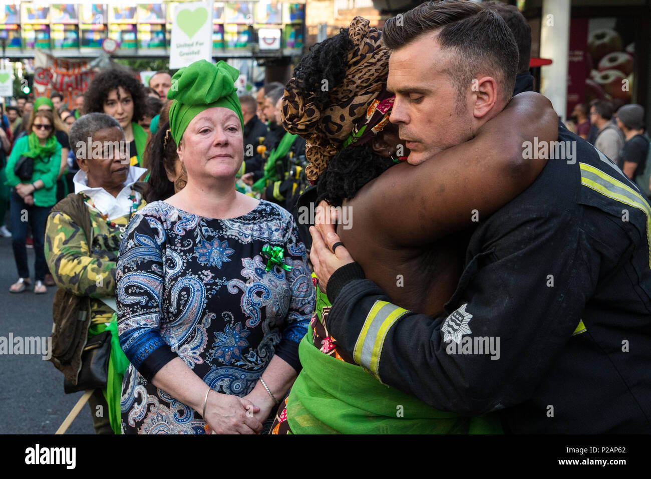 London, Großbritannien. 14 Juni, 2018. Mitglieder der Grenfell Gemeinschaft vielen Feuerwehrmänner vom Londoner Feuerwehr bilden ein Spalier für die Grenfell Schweigemarsch durch West Kensington am ersten Jahrestag der Grenfell Turm Feuer. 72 Menschen in der Grenfell Turm Feuer und über 70 Tote wurden verletzt. Credit: Mark Kerrison/Alamy leben Nachrichten Stockfoto