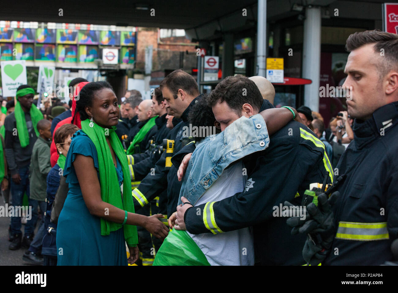 London, Großbritannien. 14 Juni, 2018. Mitglieder der Grenfell Gemeinschaft vielen Feuerwehrmänner vom Londoner Feuerwehr bilden ein Spalier für die Grenfell Schweigemarsch durch West Kensington am ersten Jahrestag der Grenfell Turm Feuer. 72 Menschen in der Grenfell Turm Feuer und über 70 Tote wurden verletzt. Credit: Mark Kerrison/Alamy leben Nachrichten Stockfoto