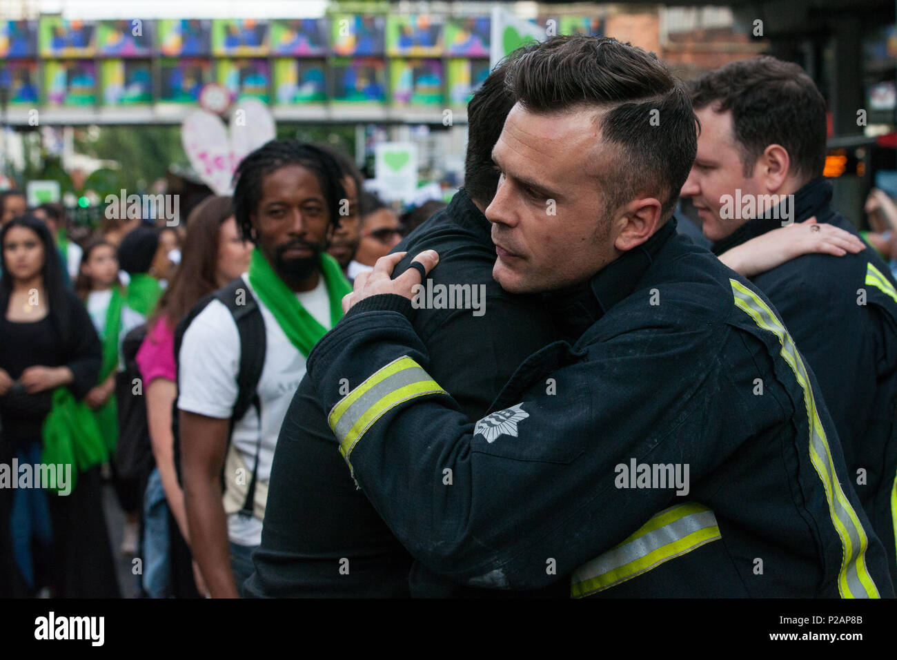 London, Großbritannien. 14 Juni, 2018. Mitglieder der Grenfell Gemeinschaft vielen Feuerwehrmänner vom Londoner Feuerwehr bilden ein Spalier für die Grenfell Schweigemarsch durch West Kensington am ersten Jahrestag der Grenfell Turm Feuer. 72 Menschen in der Grenfell Turm Feuer und über 70 Tote wurden verletzt. Credit: Mark Kerrison/Alamy leben Nachrichten Stockfoto