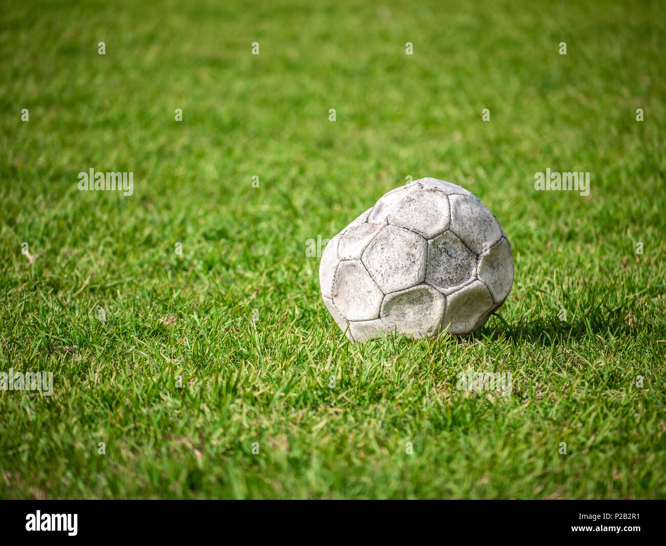 Alte leck Fußball/Fußball auf der grünen Wiese aufgegeben. Konzept der Traurigkeit, Hoffnungslosigkeit und Einsamkeit. Stockfoto
