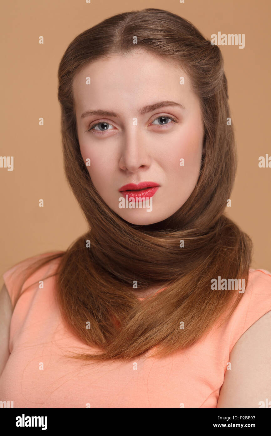 Frau Klopapier Haar um den Hals und auf Kamera. Portrait von emotionalen Cute, schöne Frau mit Make-up und langes Haar in rosa Kleid. Studio s Stockfoto