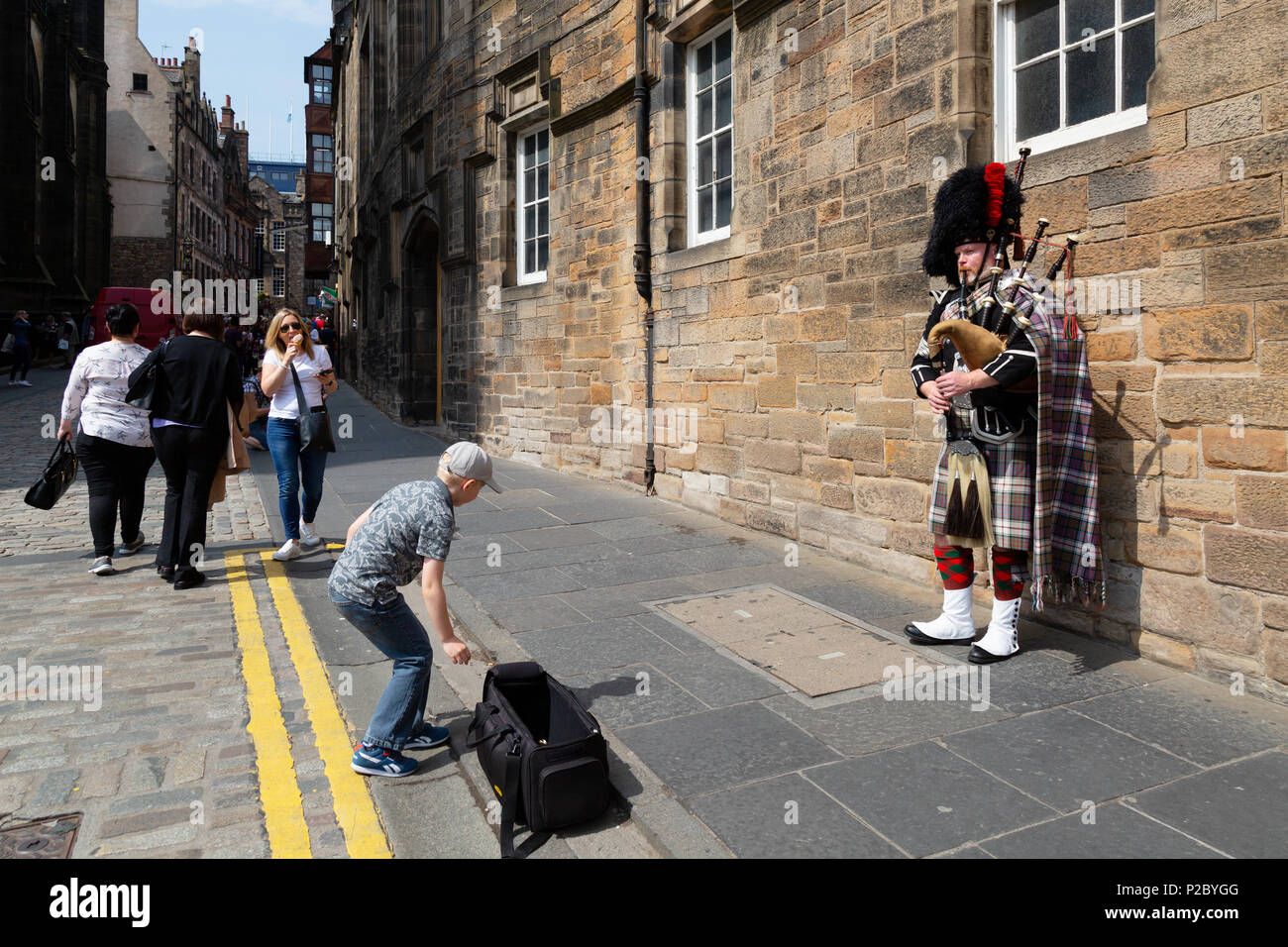 Kind Geld zu geben, ein dudelsackspieler Straßenmusik, die Royal Mile, Edinburgh Altstadt zum Weltkulturerbe der UNESCO, Edinburgh Schottland Großbritannien Stockfoto
