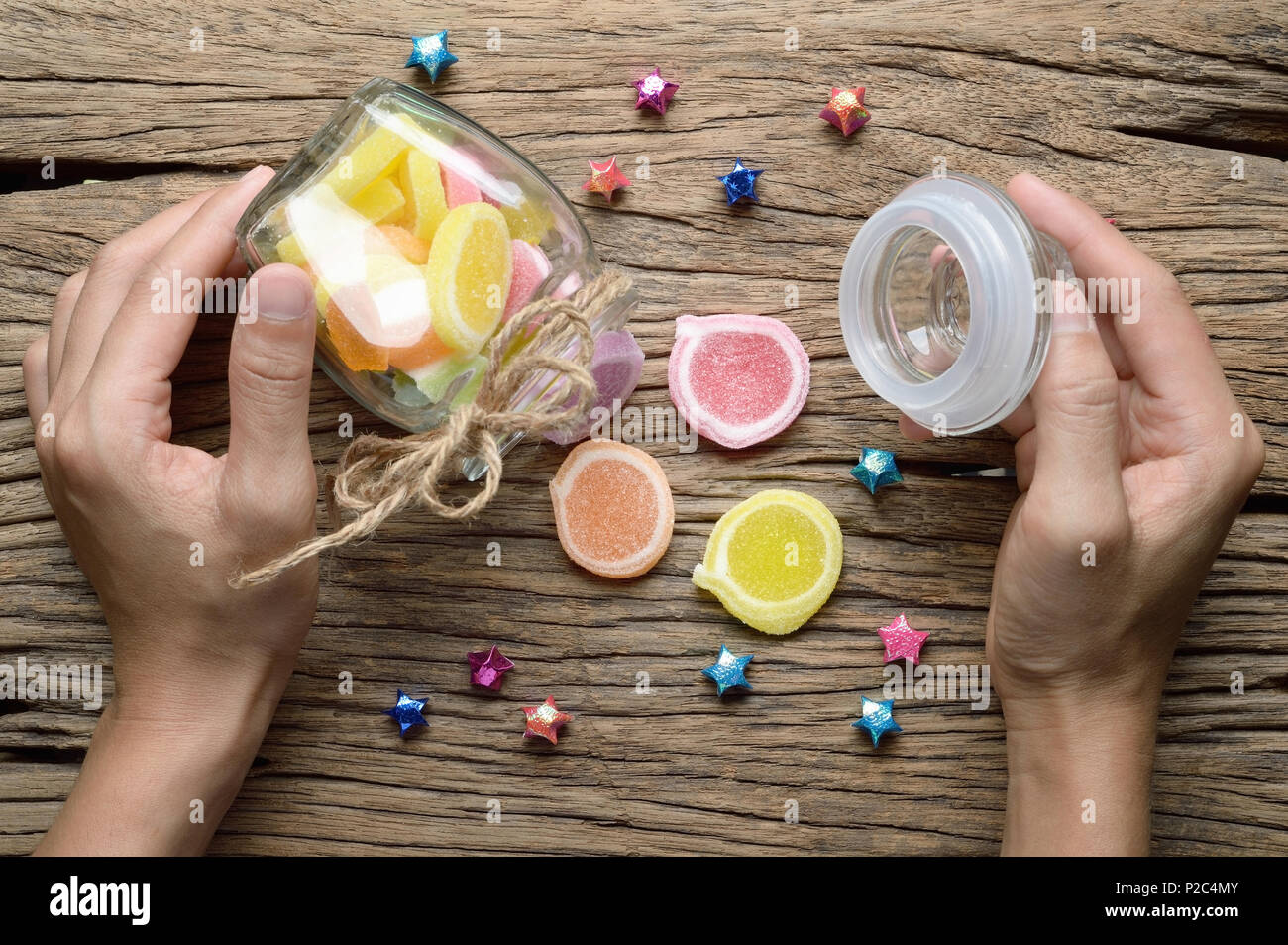 Blick von oben auf die Frau Hand offen Glas Flasche jelly candy Dessert auf Holz- Hintergrund Stockfoto