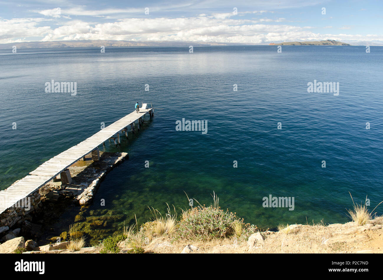 Ein cholita, ein gebürtiger Frau in traditioneller Kleidung, stehend auf einem Steg auf der Insel Isla del Sol, Titicacasee, Bolivien Stockfoto