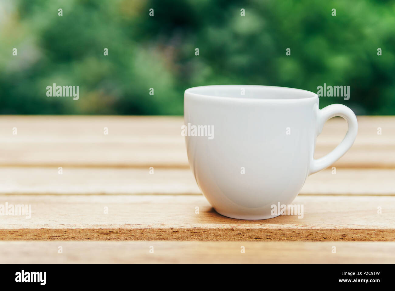 Weiß Kaffeetasse auf hölzernen Tisch in grünen Garten Stockfoto