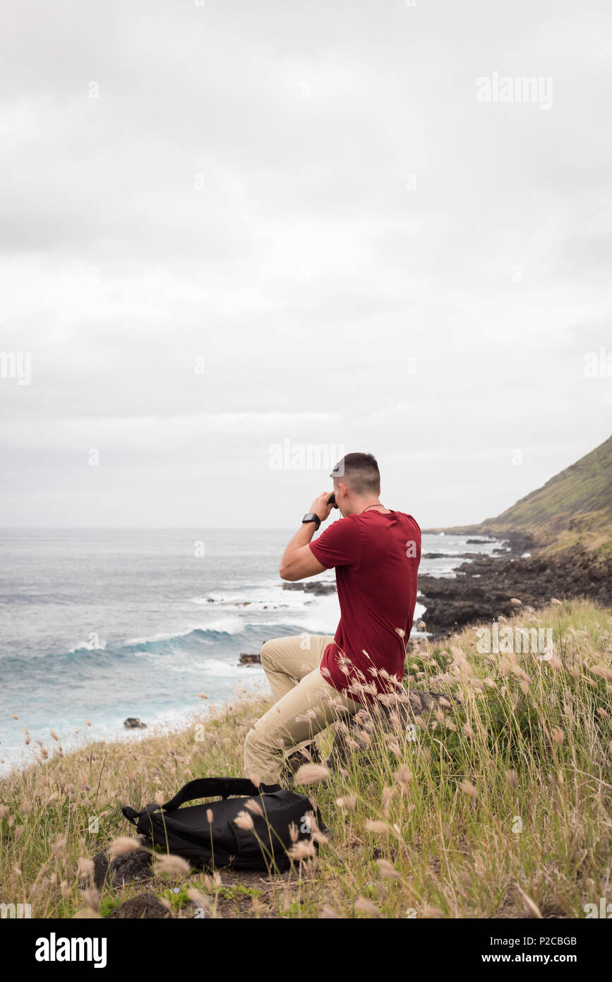 Mann schaut durch ein Fernglas in der Landschaft Stockfoto