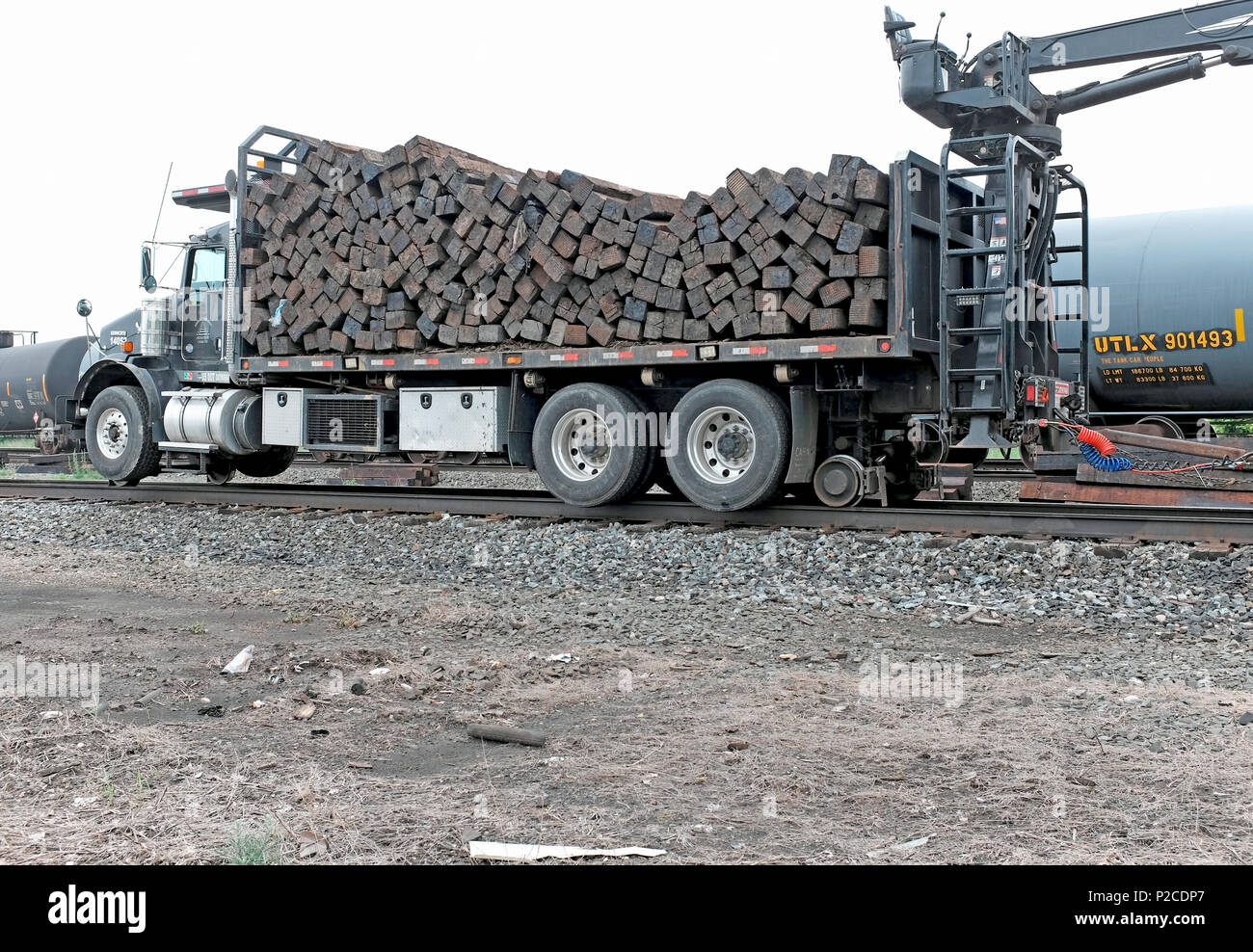 Logging Truck mit Holzplanken neben Eisenbahnschienen in der Innenstadt von Cleveland, Ohio, USA gefüllt. Stockfoto
