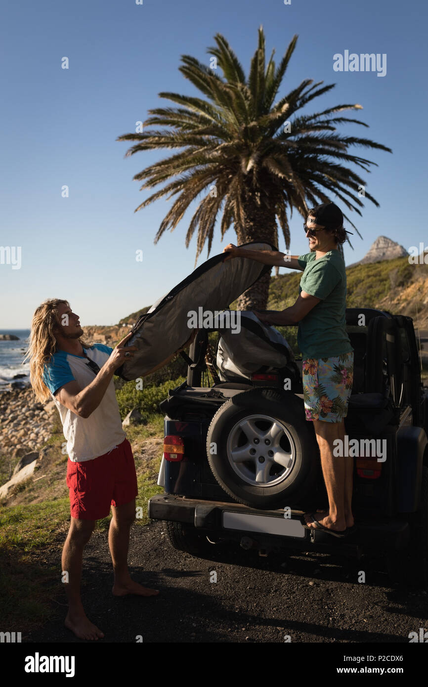 Männliche Freunde Surfboard entfernen, die von dem Jeep Stockfoto