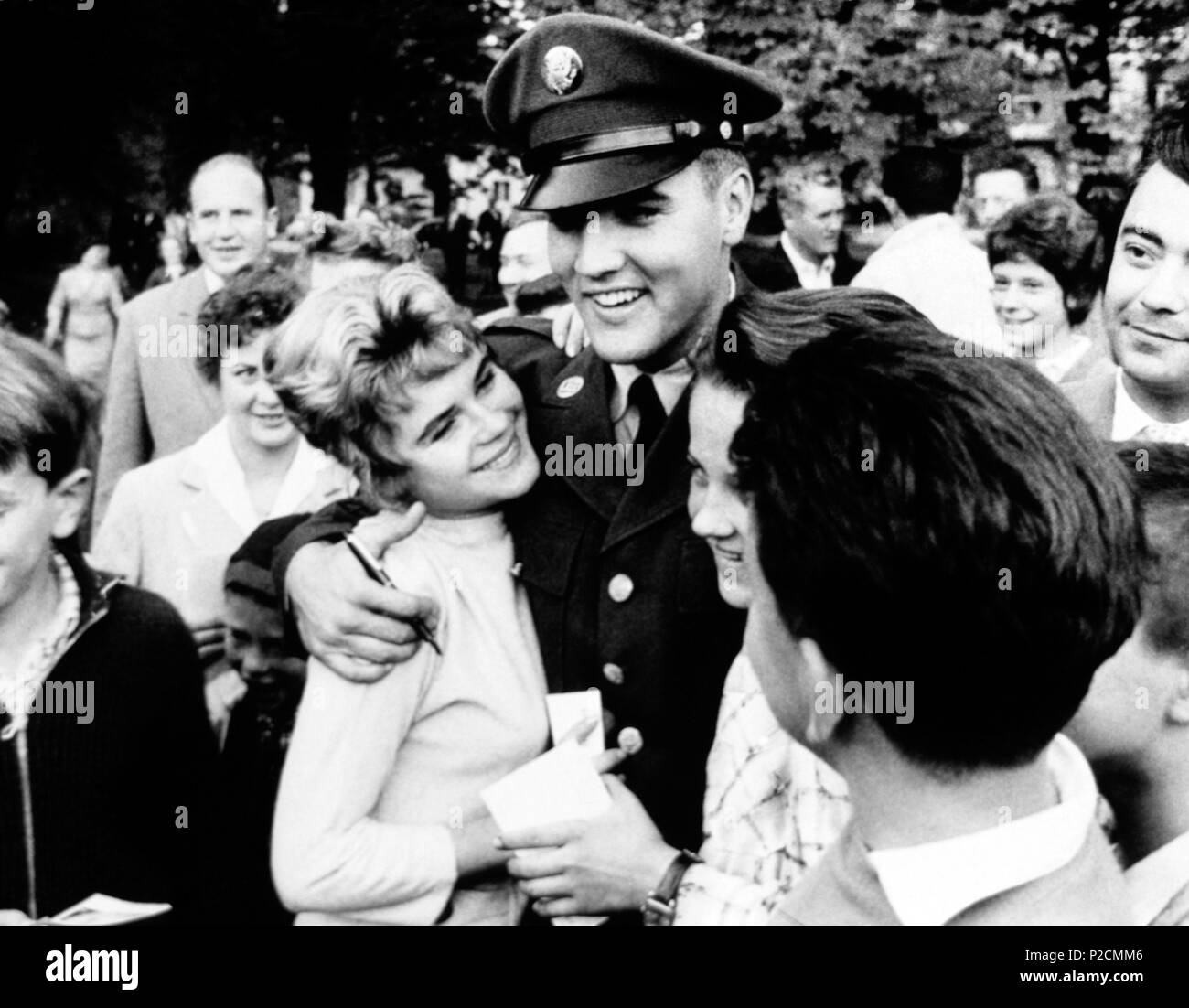 Der amerikanische Sänger Elvis Presley mit seinen Fans in einem Park von Deutschland während seiner Militärzeit bei der Ray Barracks in 1958. Stockfoto