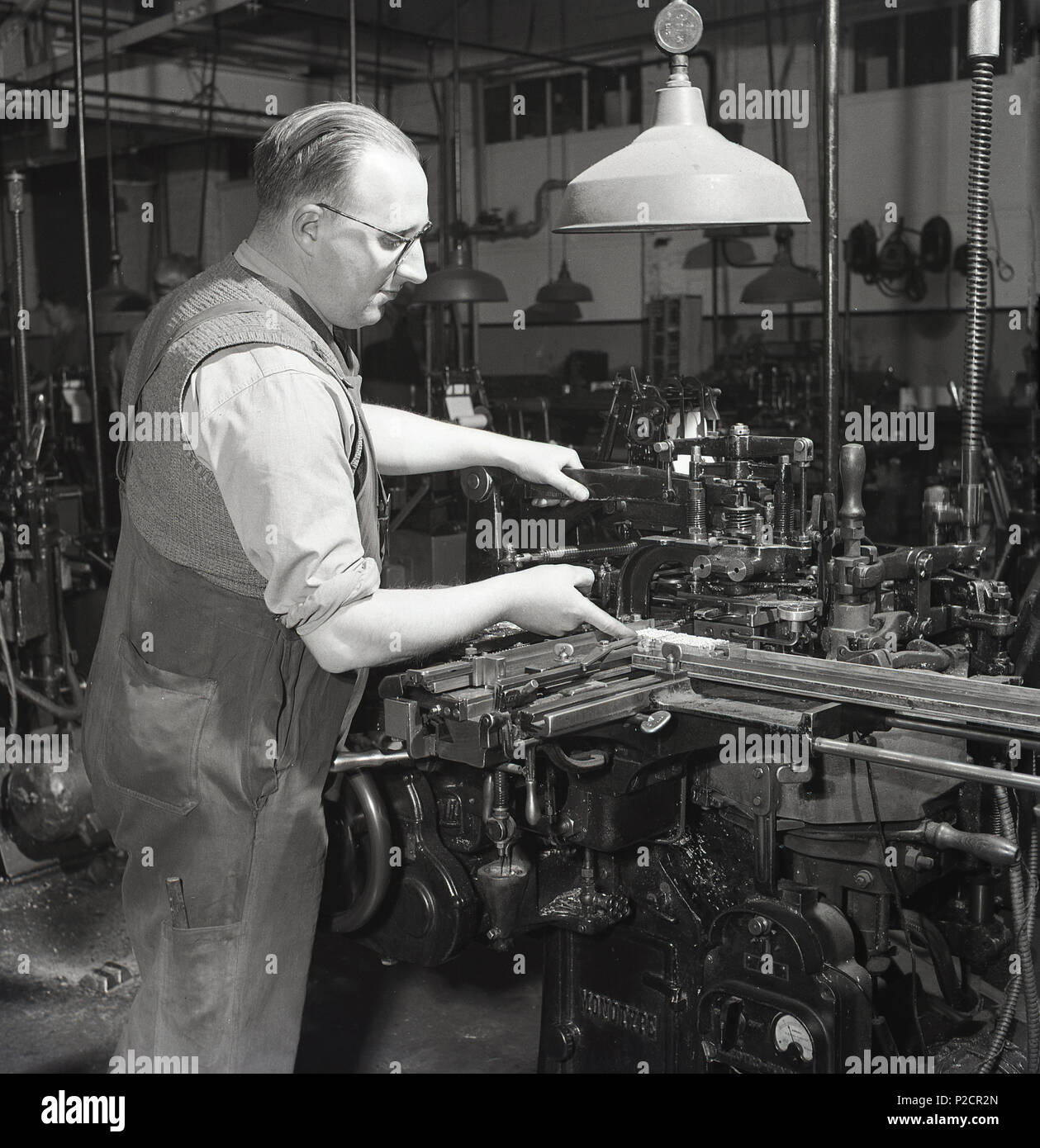 1950er Jahre, historische, ein Mann, der Arbeiter, die die komplizierte mechanische Maschinen in einer Fabrik der Ära England, UK. Stockfoto