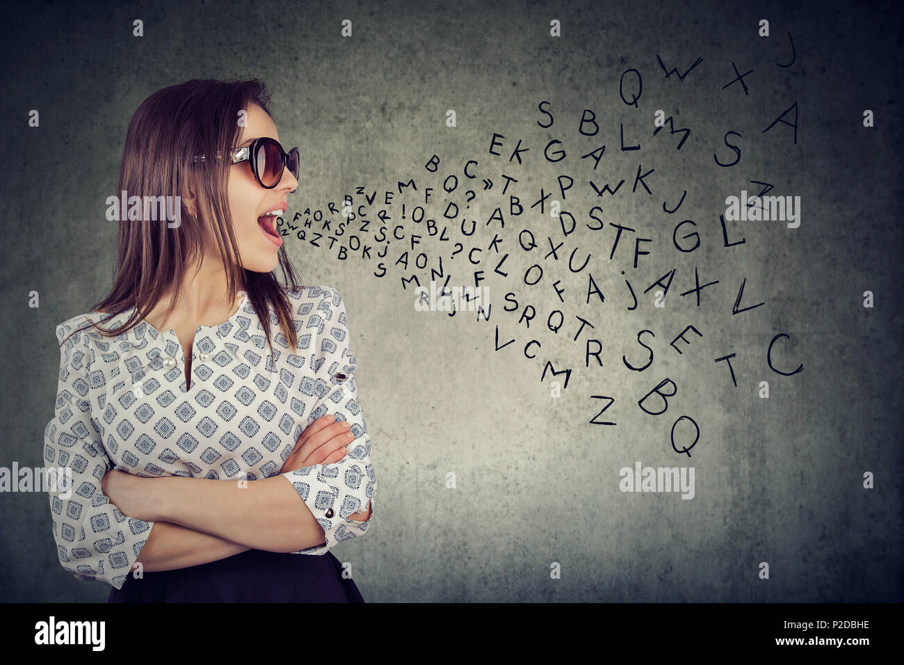 Frau in Sonnenbrille im Gespräch mit Buchstaben des Alphabets aus ihrem Mund kommen. Kommunikation, Information, Konzept Stockfoto