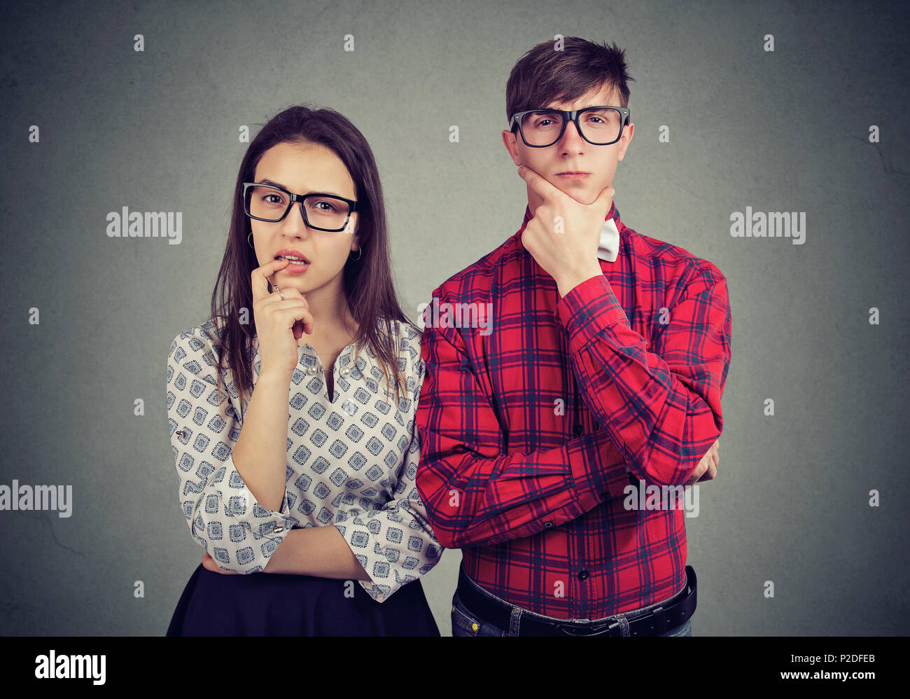 Junge exzentrische Mann und Frau suchen Verdächtige beim Stehen auf grau und Kamera durch eine Brille. Stockfoto