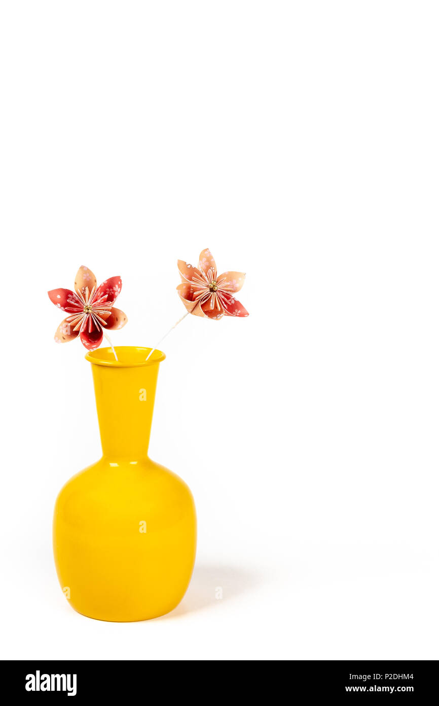 Nahaufnahme von zwei orange origami Blumen in gelb Topf auf weißem Hintergrund. Stockfoto
