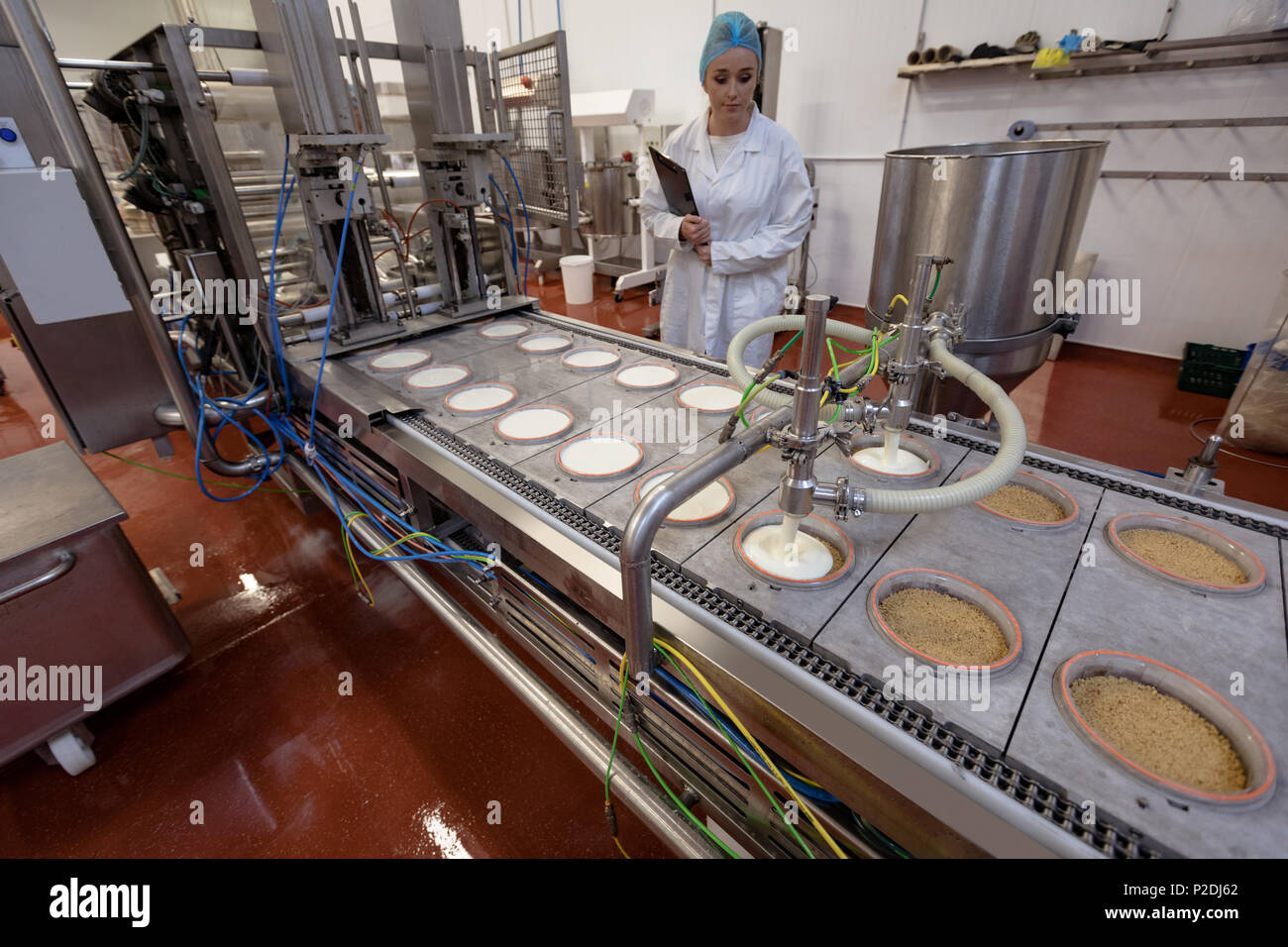 Weibliche Arbeitnehmer überwachung Lebensmittel in der Nähe von Produktionslinie Stockfoto
