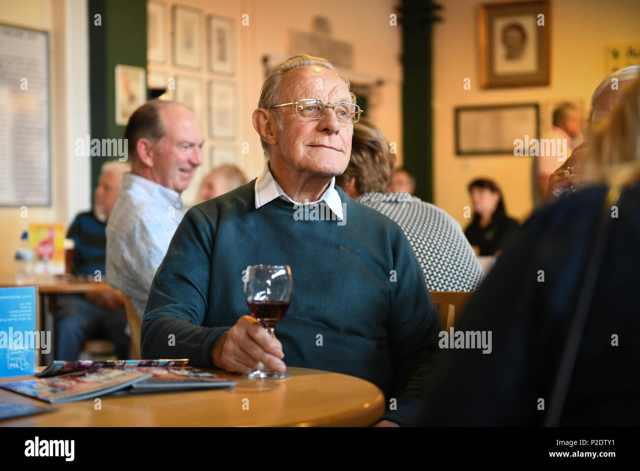 Ein Mann von Alter sitzt weg von der Kamera ein Glas Rotwein an einem Tisch genießen. Stockfoto