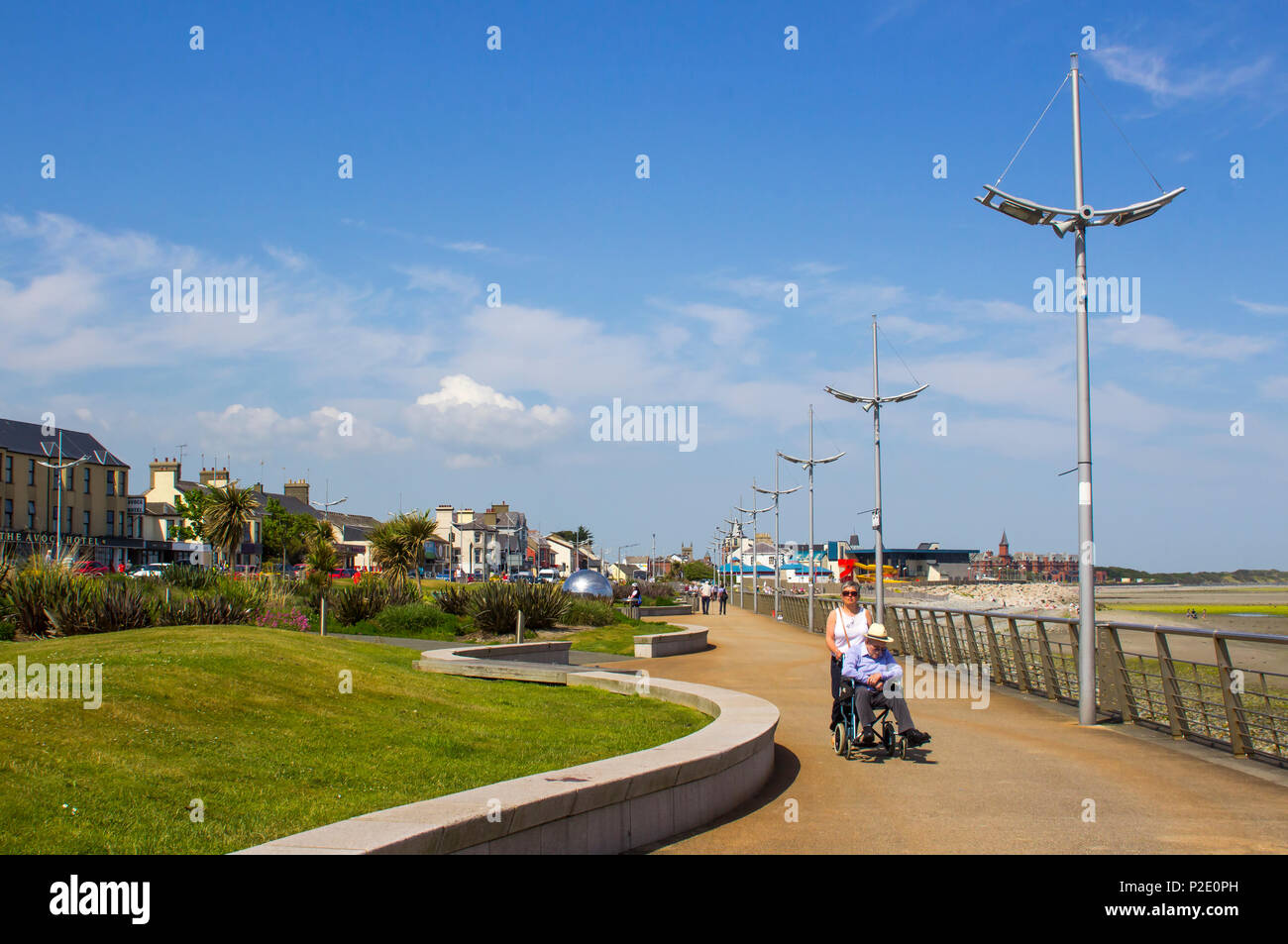 Vom 7. Juni 2018 Ein Mann Schieberollstuhl ist seine Partnerin in der Sonne an der Promenade von Newcastle County Down in Nordirland Stockfoto