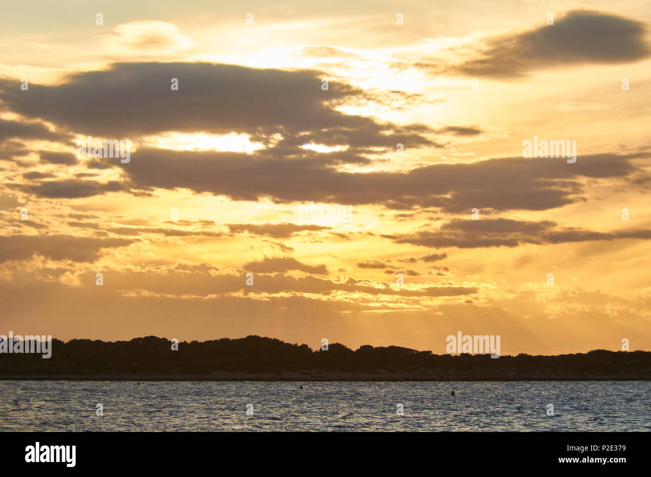 Golden Sunset am Caló de s'Oli mit Sonnenstrahlen und hinterleuchteten Wolken von Sa Boca in Ses Salines Naturpark (Formentera, Balearen, Spanien) Stockfoto