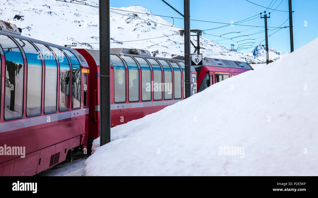 Bernina Express Zug, einer der höchsten Bahn der Welt, geht über die schneebedeckten Berge zwischen Italien und der Schweiz Stockfoto