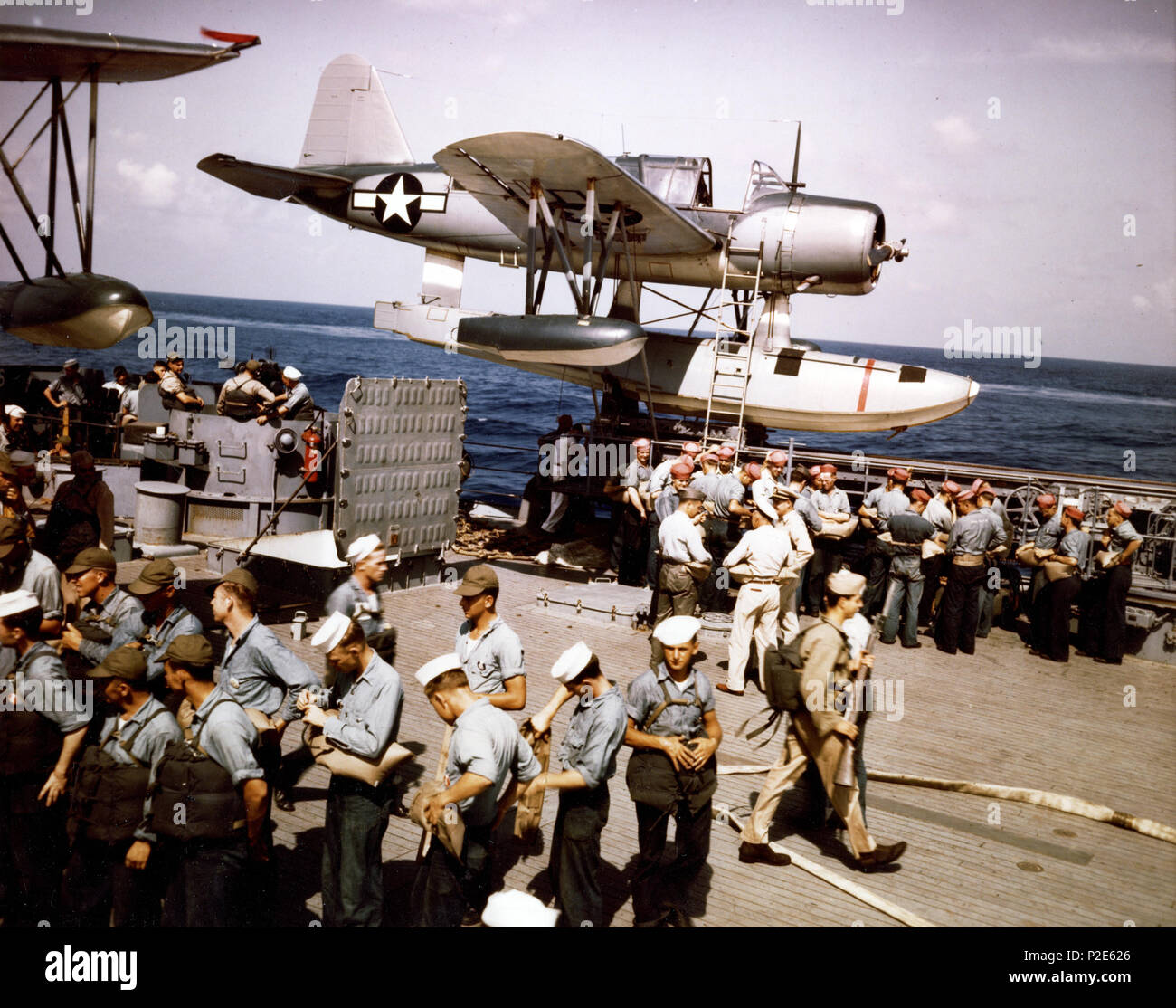 . Blick auf eine Übung zum Verlassen des Schiffes auf dem Achterdeck der U.S. Navy battleship USS Missouri (BB-63), während Ihrer shakedown Zeitraum im Sommer 1944. Hinweis Die Vought OS2U Kingfisher Wasserflugzeug (eigentlich ein Naval Aircraft Factory OS2 N-1) auf der Backbordseite Katapult; die Vielfalt der rettungsring Typen; der Baseball Kappen und die rot weißen Hüte durch einige Segler getragen; die Marine zu Fuß, mit einer M-1 Gewehr, und öffnen Sie die Klappe. Sommer 1944. USN 39 OS2 N-1 auf Cat der USS Missouri (BB-63) im Sommer 1944 Stockfoto