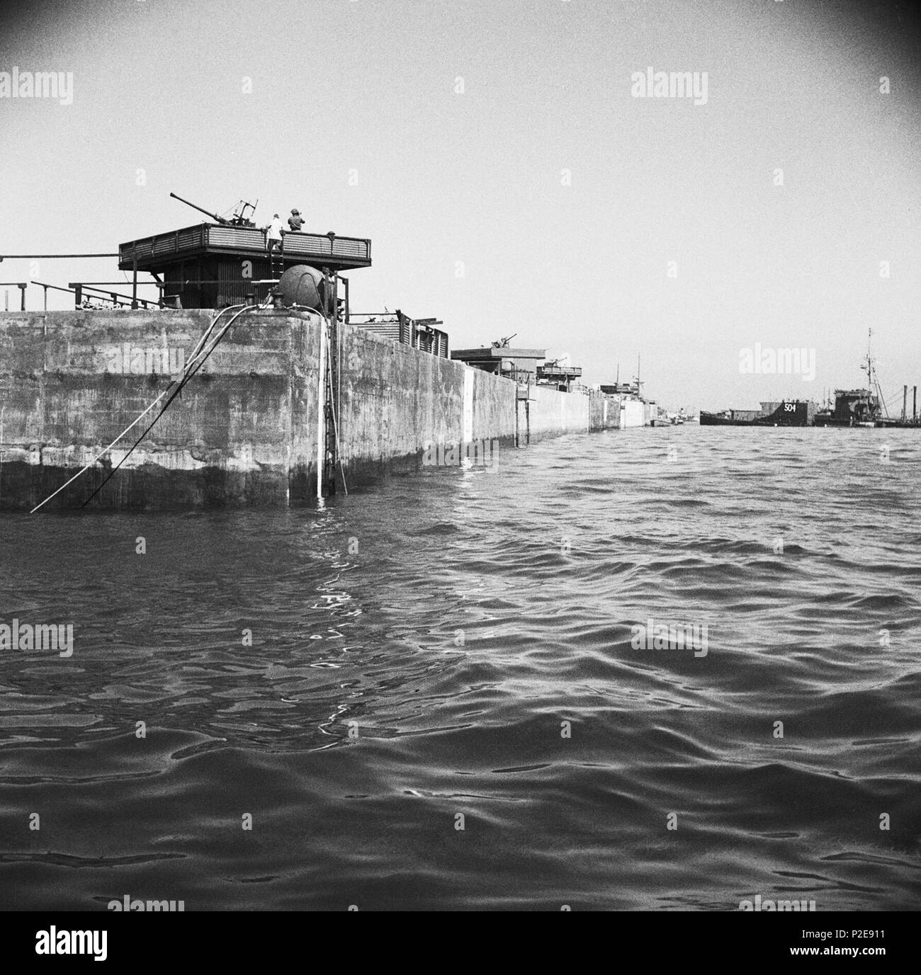 Eine Linie von Phoenix Caissons in Arromanches, mit Flugabwehrraketen installiert. Juni 12, 1944 Stockfoto
