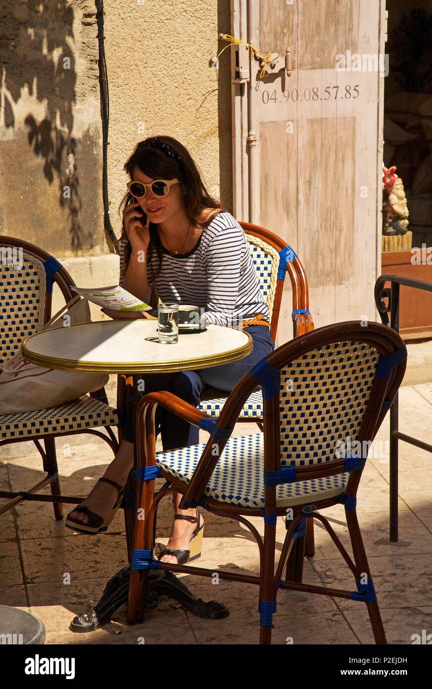Frankreich, Vaucluse, Luberon, Lourmarin, Mädchen mit Sonnenbrille auf der Terrasse einen Kaffee in einer Gasse des alten Dorfes Stockfoto
