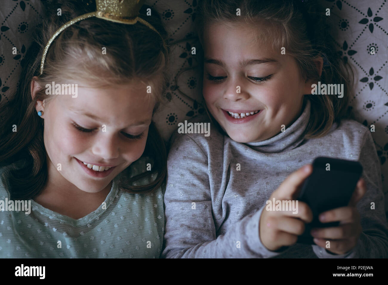 Geschwister mit Handy auf dem Bett Stockfoto