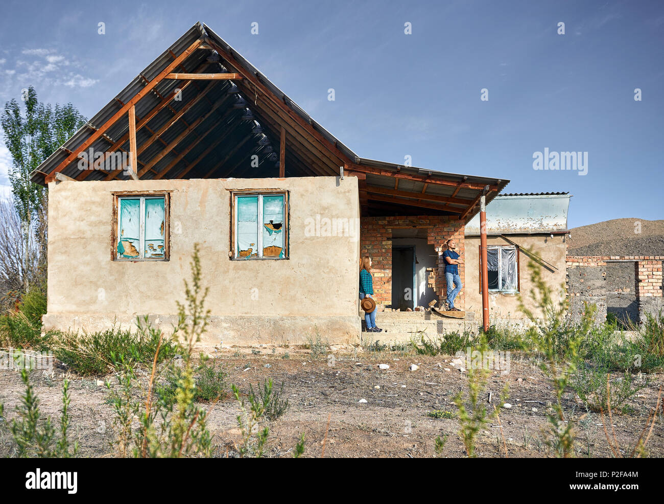 Frau mit Hut und Mensch in kariertes Hemd auf den Ruinen der alten Haus im Dorf Stockfoto