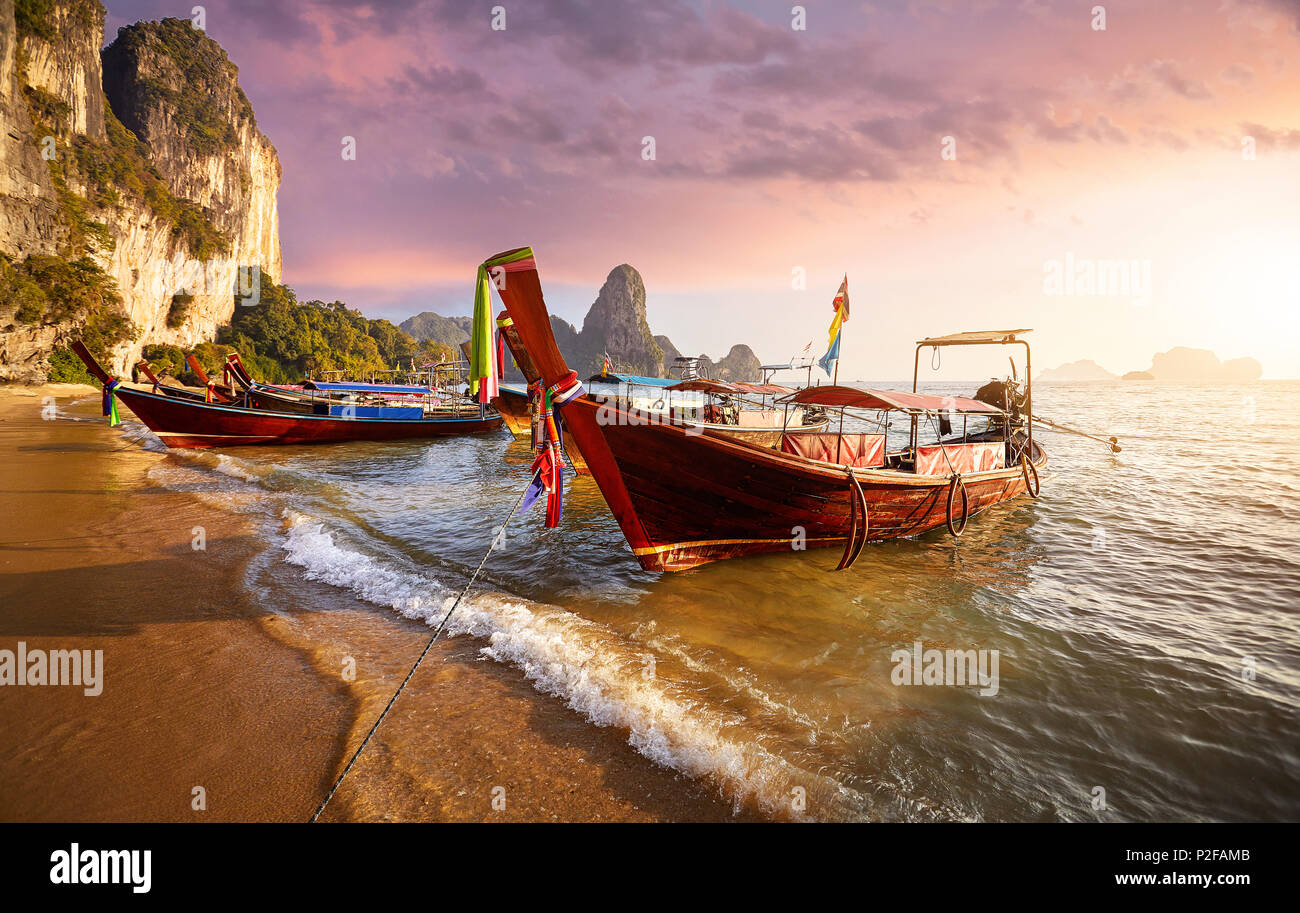 Long tail Boote am tropischen Strand bei Sonnenuntergang in Thailand Stockfoto