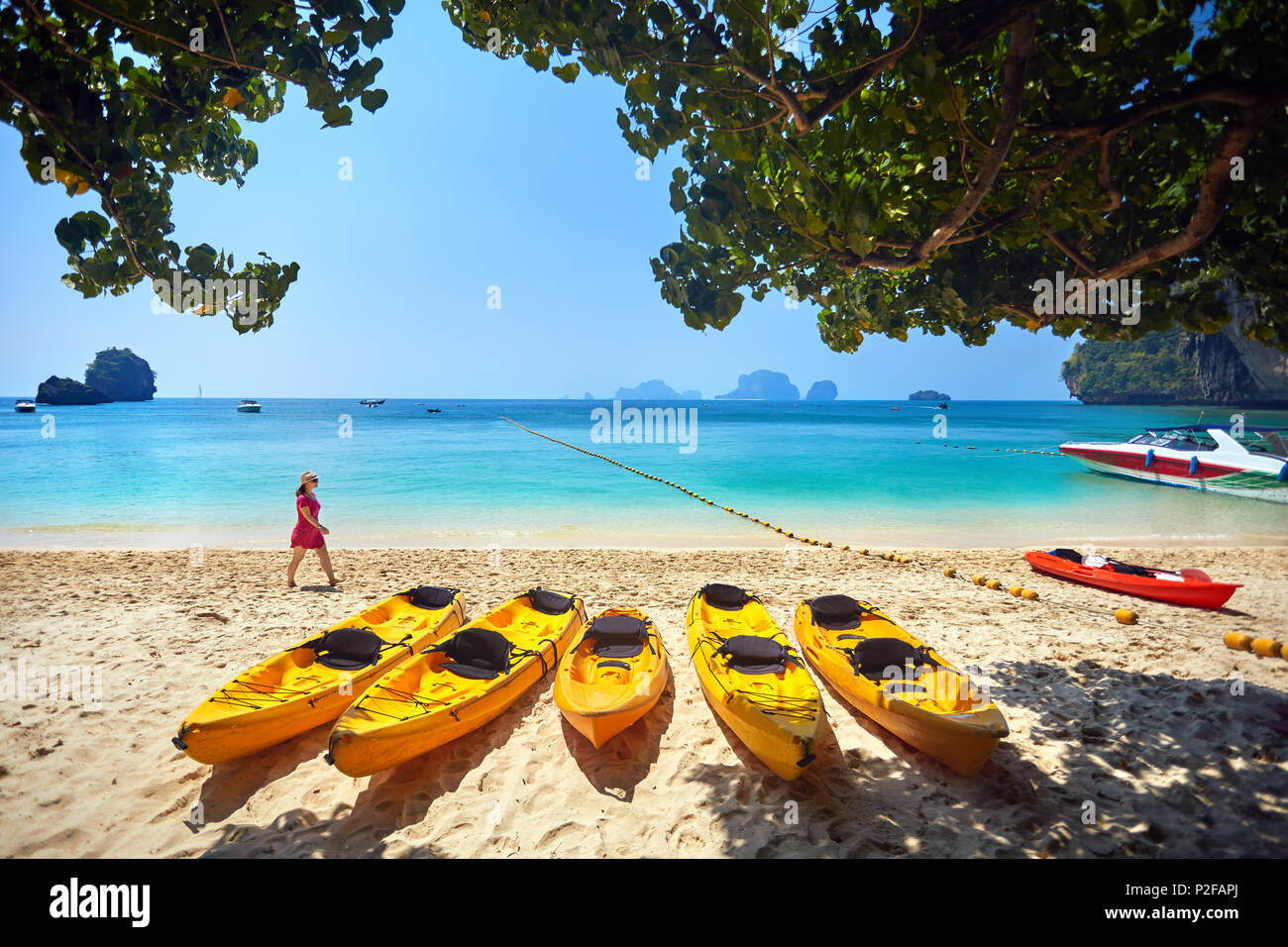 Frau im rosa Kleid zu Fuß auf der Phranang Beach mit gelben Kajak Boot in Thailand Stockfoto